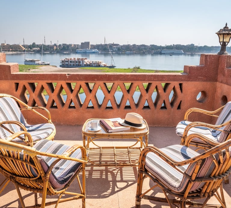 Luxury balcony terrace with wicker chairs overlooking a scenic Nile River cruise in Egypt.