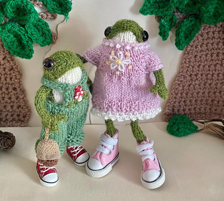 a couple of knitted frogs in a row of knitted toys