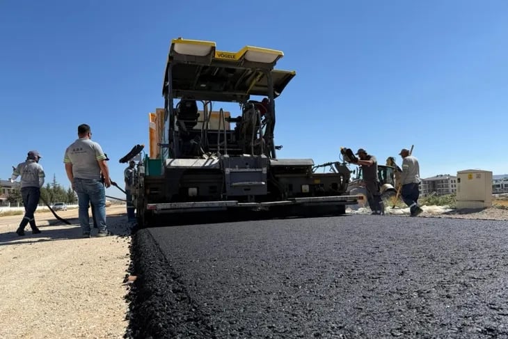 Vögele marka asfalt serici makine, yeni bir yol inşaat şantiyesinde işçilerle birlikte taze siyah as