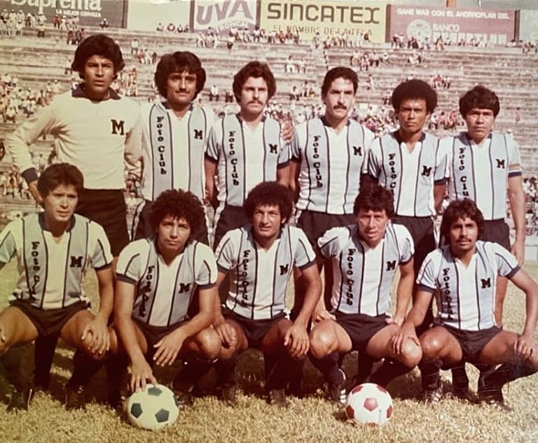 Vintage team photo of a classic soccer squad in light blue striped jerseys posing on the pitch.