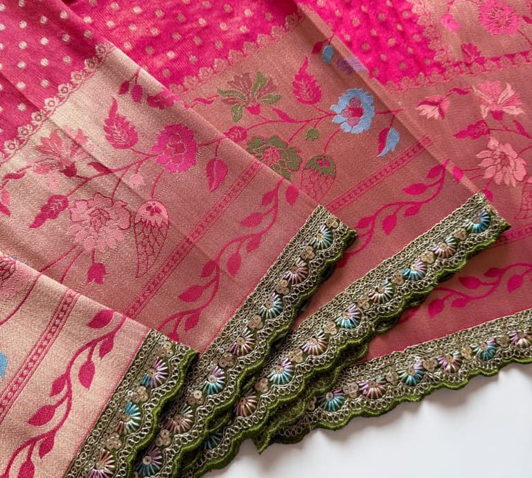 Elegant pink and mauve Banarasi silk saree with floral embroidery and a green scalloped border.