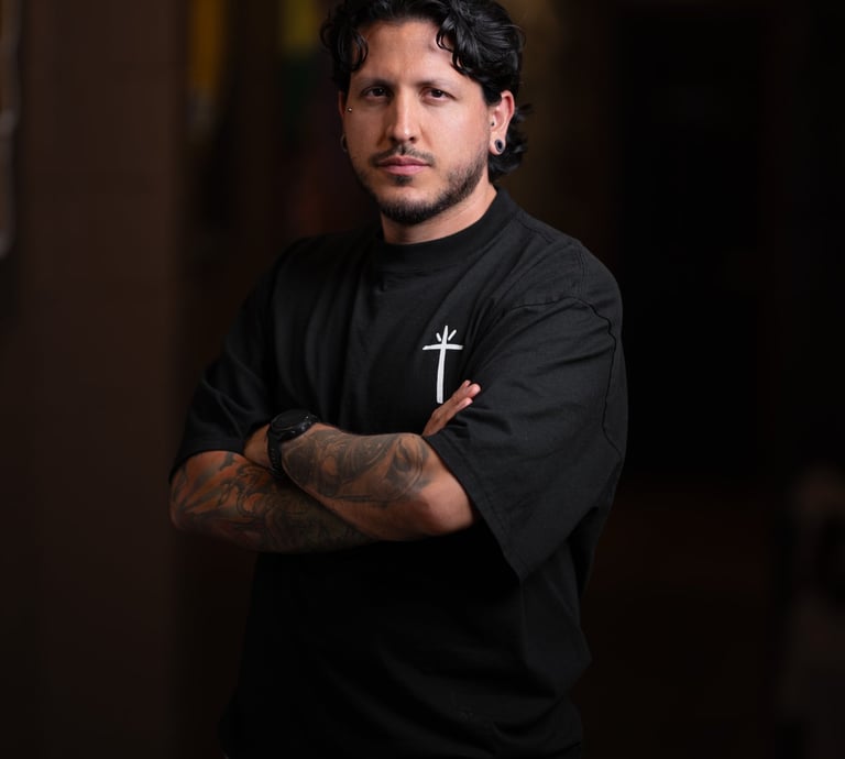 a man with tattoos on his arms and arms crossed, with a cross on his