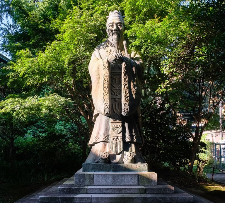 stone statue depicting Confucius in a forest