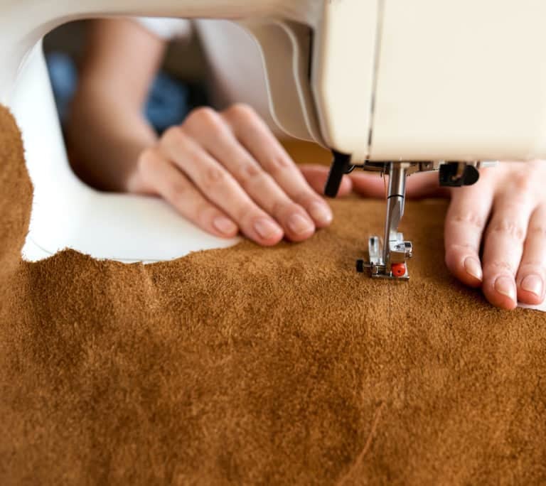 person sewing brown leather