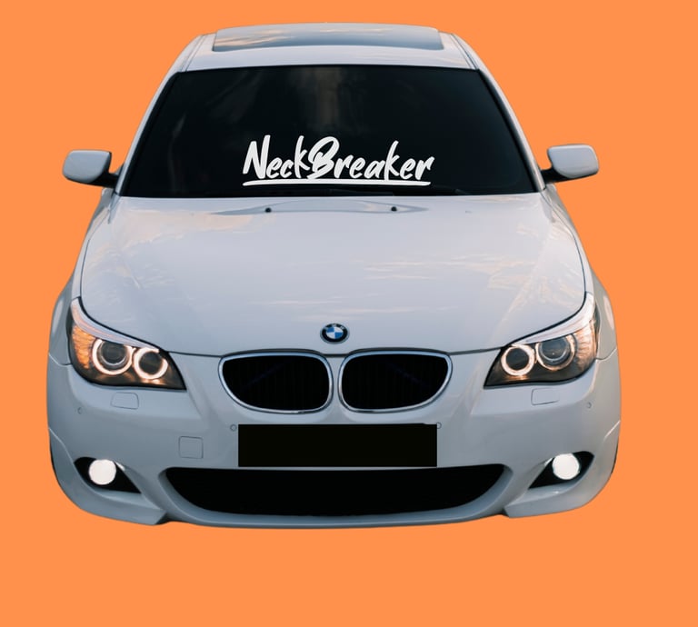 White modified BMW E60 with Neckbreaker windshield decal and halo headlights on orange background.