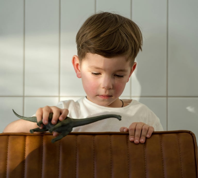 a young boy sitting in a suitcase with a dinosaur toy