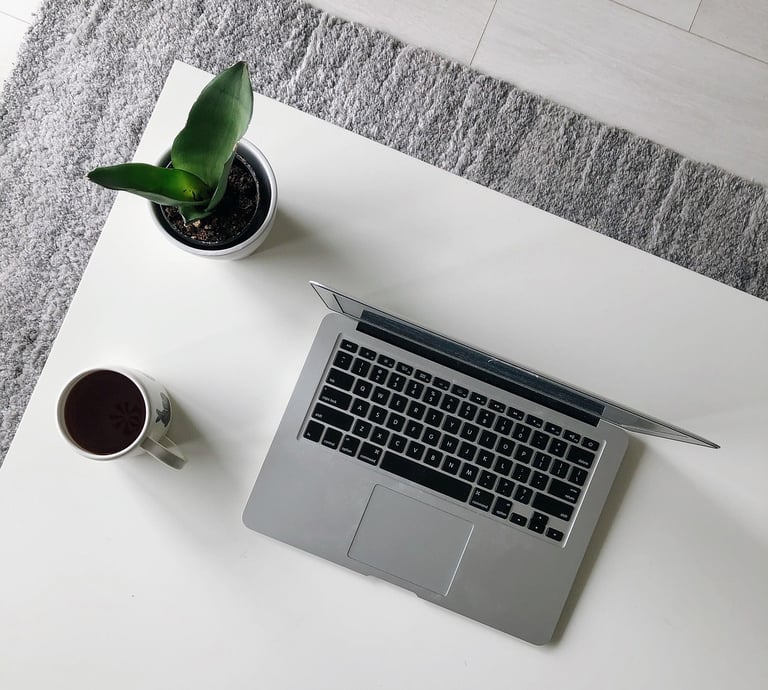 a laptop computer sitting on a table with a cup of coffee and a plant