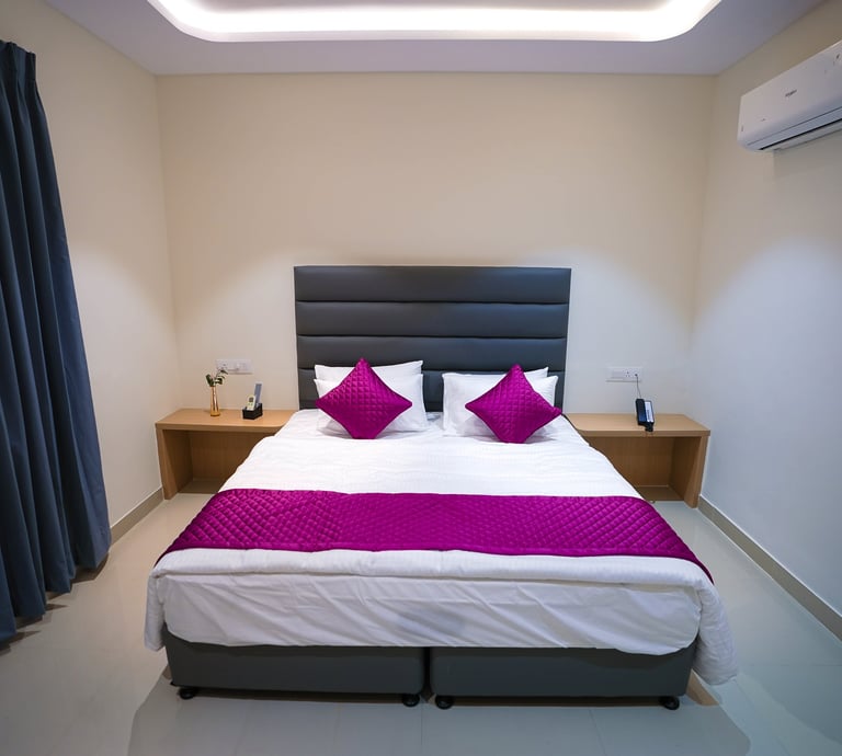 Modern hotel room with a queen bed, purple accents, and air conditioning.