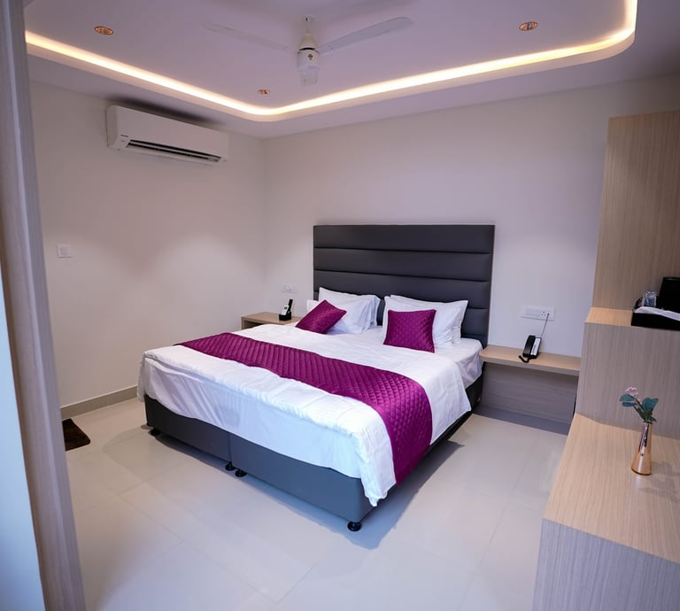 Modern hotel room featuring a king bed with purple accents and ambient cove lighting.