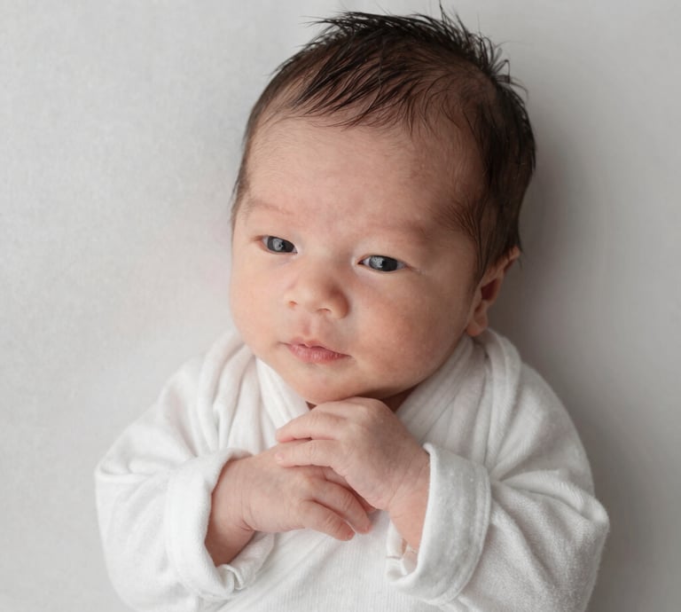 A cozy scene of a toddler wearing a soft beige sweater and sage green pants, sitting on a cream-colored blanket.