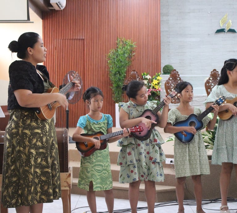  Female teacher and little girls performing ukelele