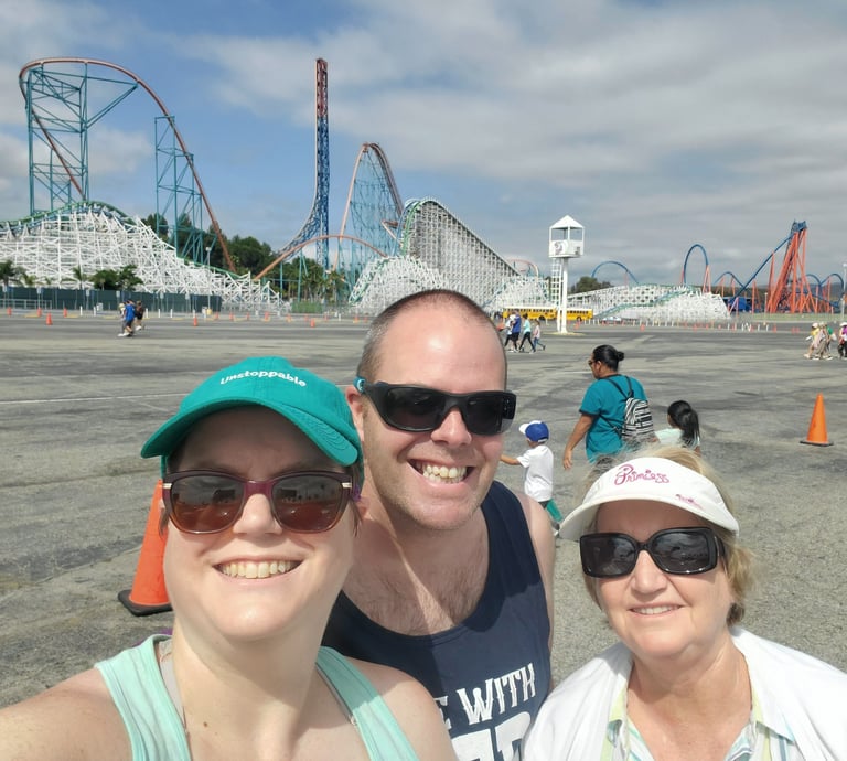 Three people standing in front of a roller coaster