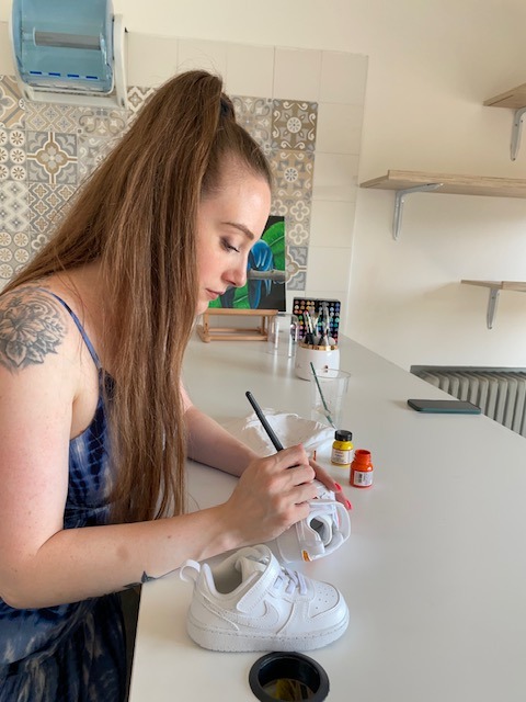 Ragazza di profilo che realizza custom fatte a mano su scarpe Nike bianche