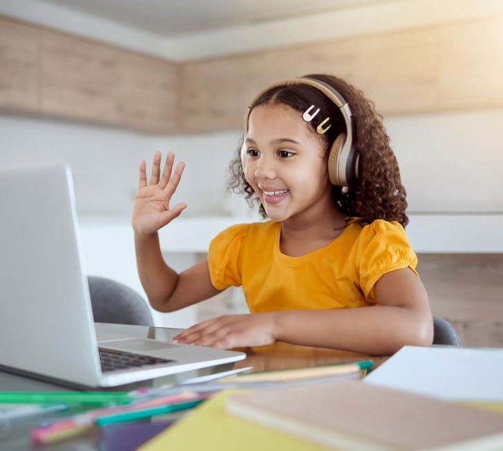 a young girl with headphones and a laptop waving hand
