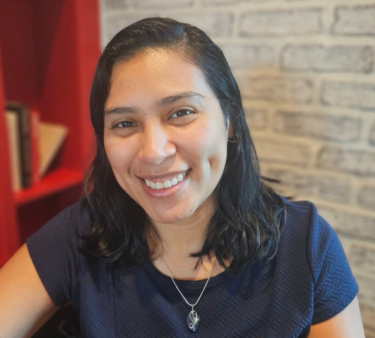 Headshot image of Karen with a bookcase and brick wall background.