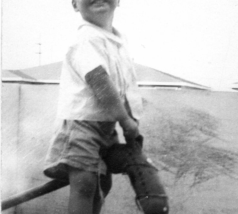 Childhood black & white photo of Cam Beard. founder of Carrots by Cam, riding a hobby horse