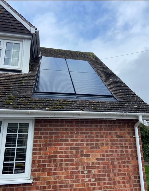 Black integrated solar panels installed on a residential tiled roof for renewable home energy.