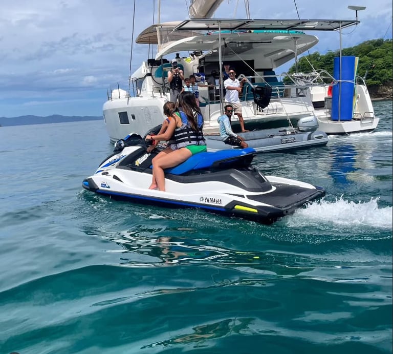 Guests riding jet skis next to Kephas catamaran during private tour in Papagayo Gulf
