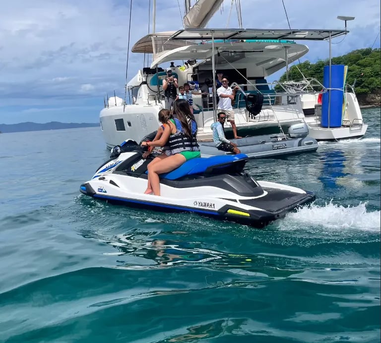Guests riding jet skis next to Kephas catamaran during private tour in Papagayo Gulf