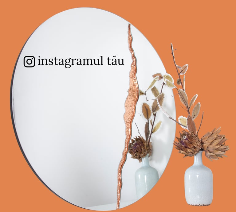 Oval wall mirror with decorative copper edge accent and a vase of dried flowers.