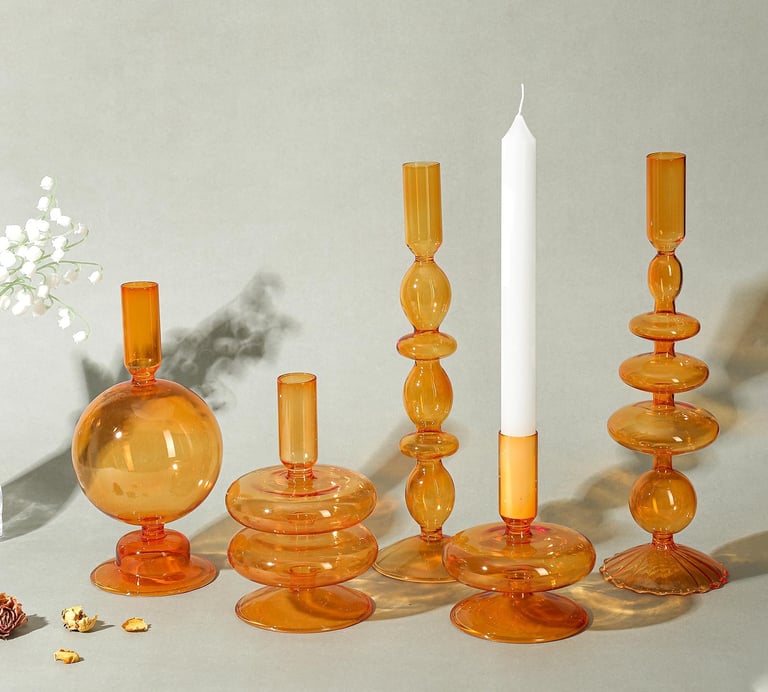 a group of candles and tapered glass candle and pillar holder
