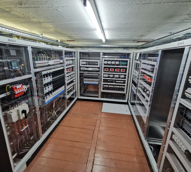 Industrial electrical control panels with circuit breakers and wiring in a power distribution room.