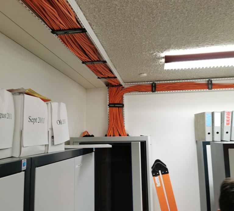 Organized orange ethernet cables managed in ceiling cable trays and server racks.