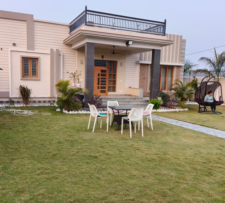 Modern luxury PG exterior featuring a green lawn, patio furniture, and balcony railing.