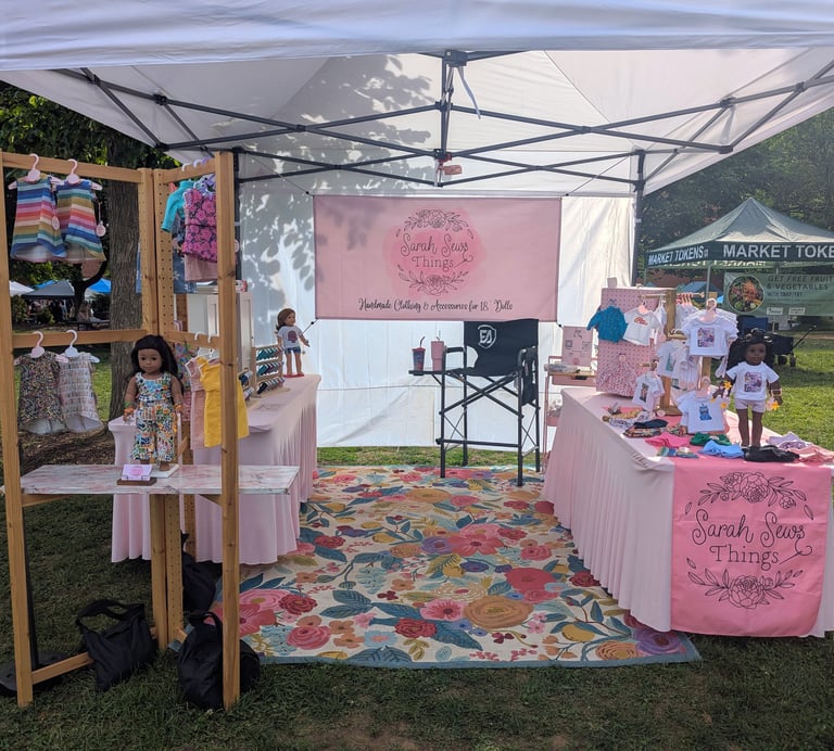 Image shows a market booth with doll clothes for sale