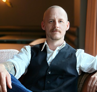 a man sitting on a couch with his arm resting on a chair