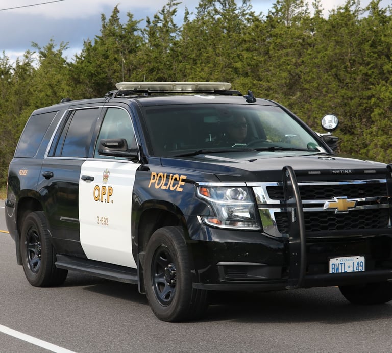 Black and white Ontario Provincial Police (OPP) Chevrolet Tahoe patrol SUV driving on a highway.