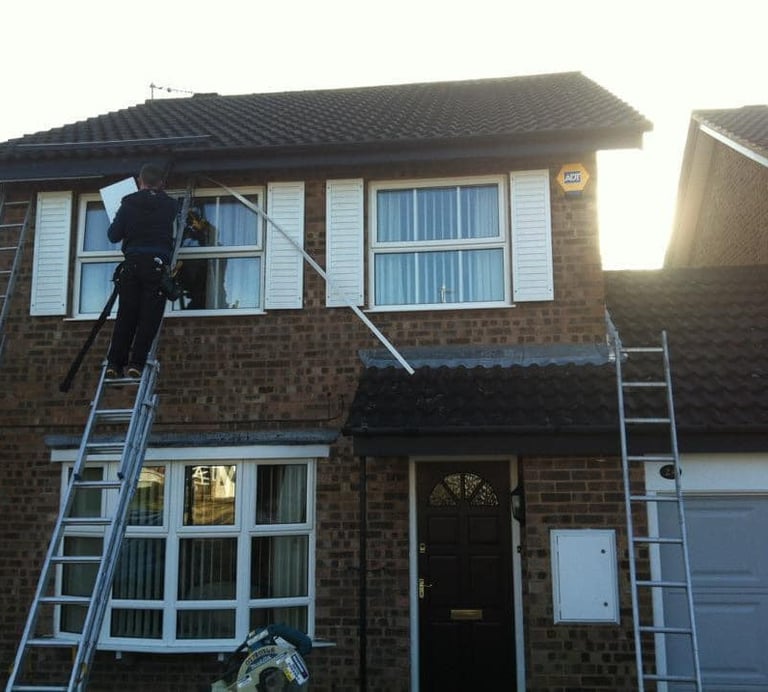 a man on a ladder ladder to reach up to a house