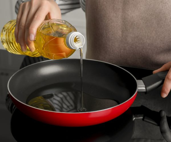 woman pouring oil in a pan on the stove