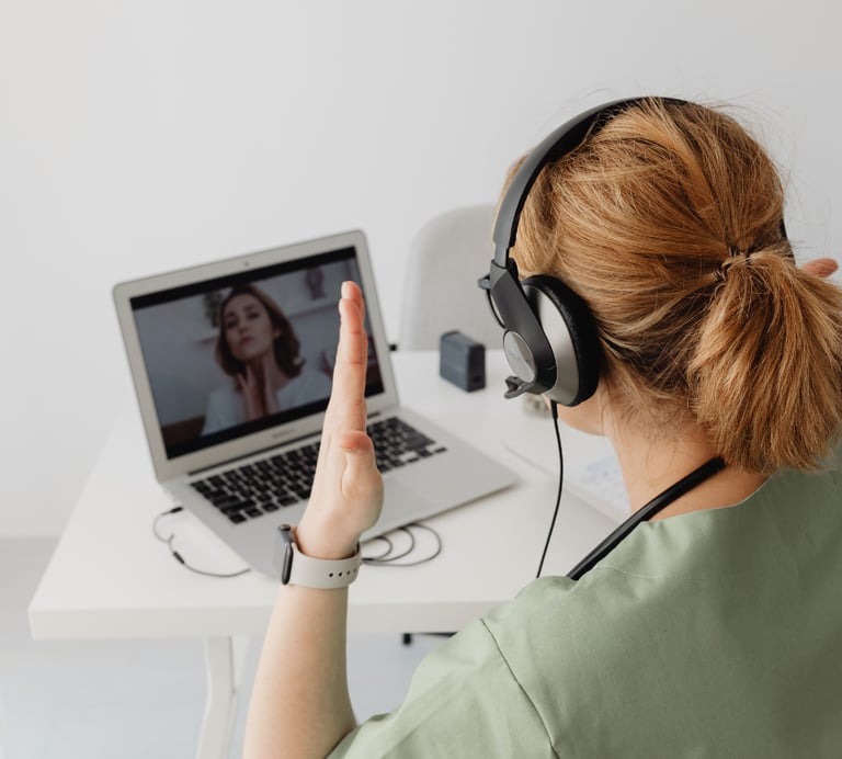 a woman in a green shirt is sitting at a desk with a laptop and head