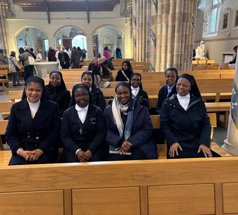 A group of Catholic nuns in habits sitting together in wooden pews inside a cathedral church.