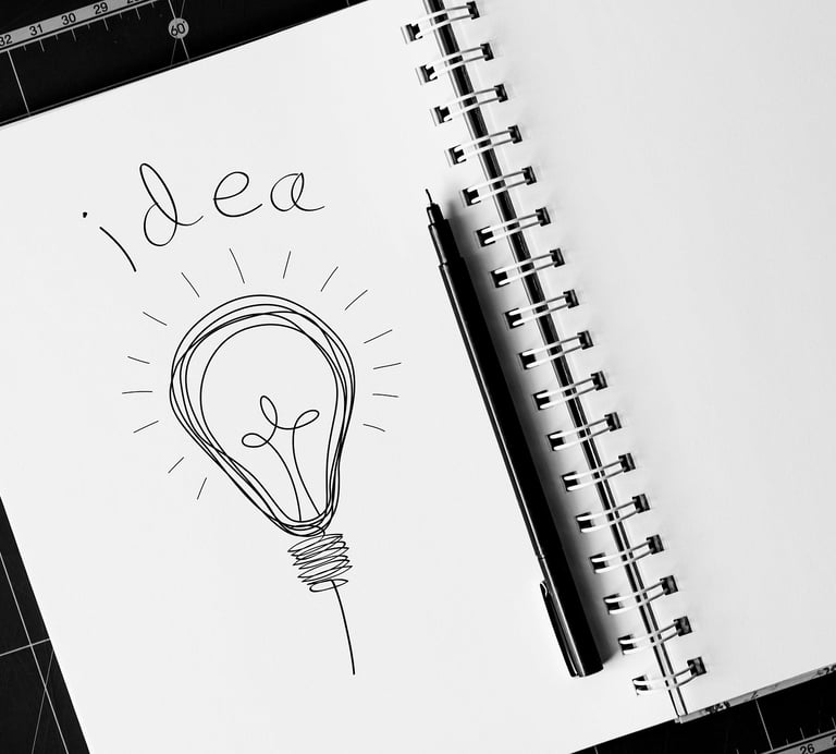 Hand-drawn light bulb sketch with the word idea in a spiral notebook, symbolizing creative brainstorming.