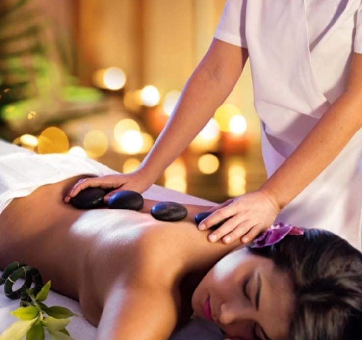 Hot stone massage treatment with smooth heated stones placed on the back in a relaxing spa