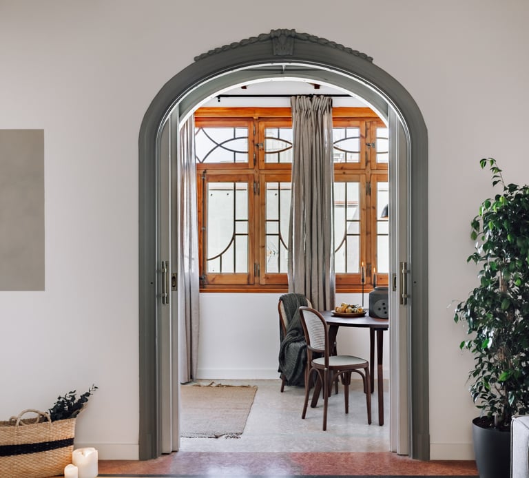 Elegant dining area with rattan and wood chairs and rustic decor elements by SAVIA interior design