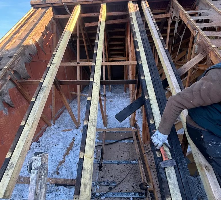 Artisan charpentier réalisant le renforcement et la rénovation d'une charpente en bois traditionnelle à Montmorency (95)