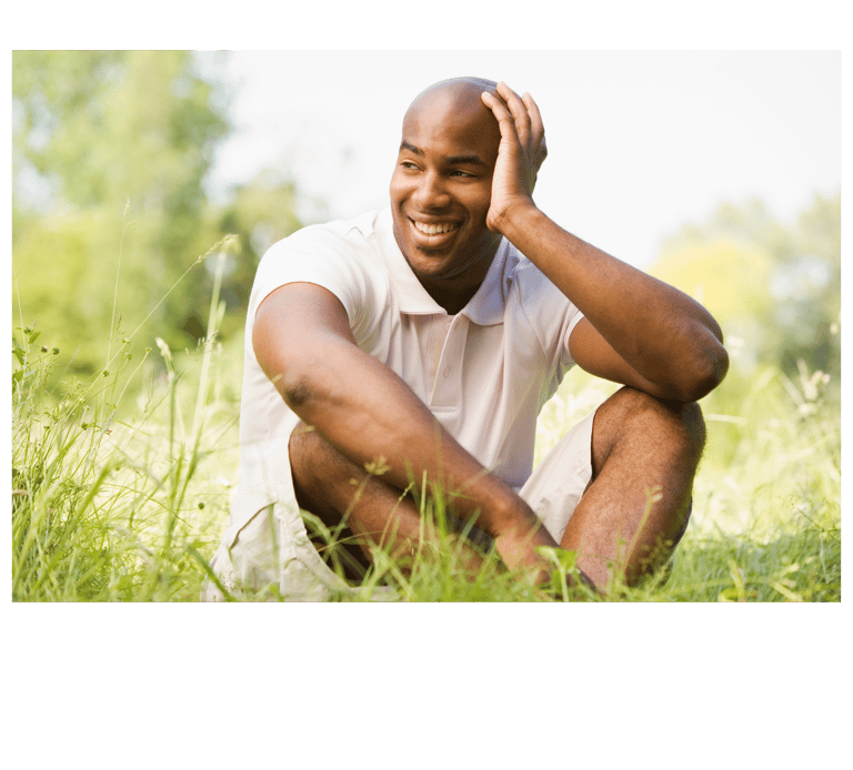 Man sitting in grass enjoying the connection to the earth: Grounding