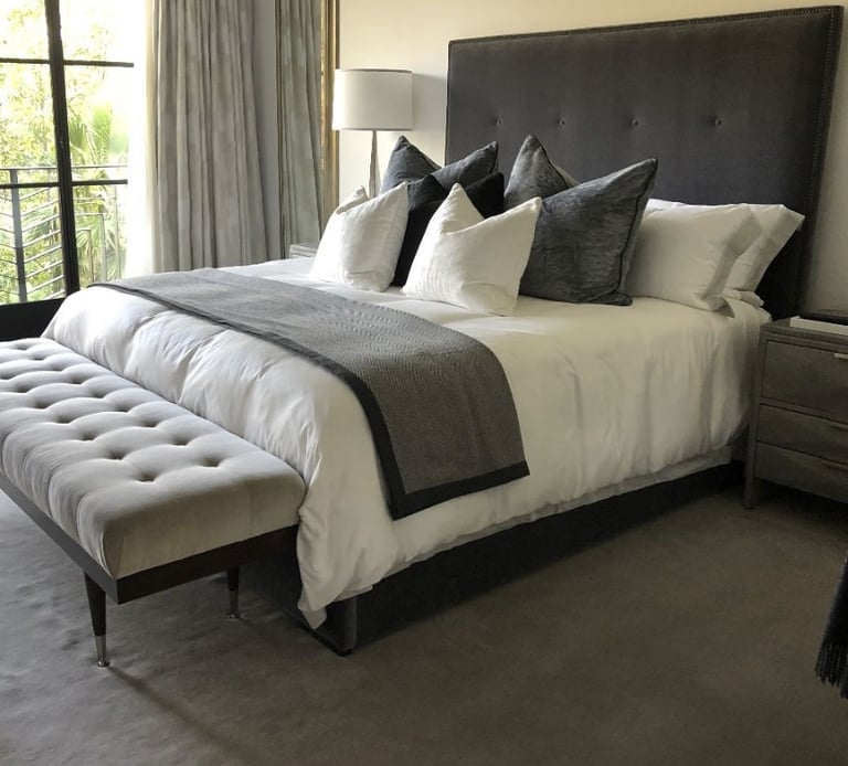 Transitional bedroom with tufted headboard, neutral bedding, and bench, designed by Solo Home Decor.