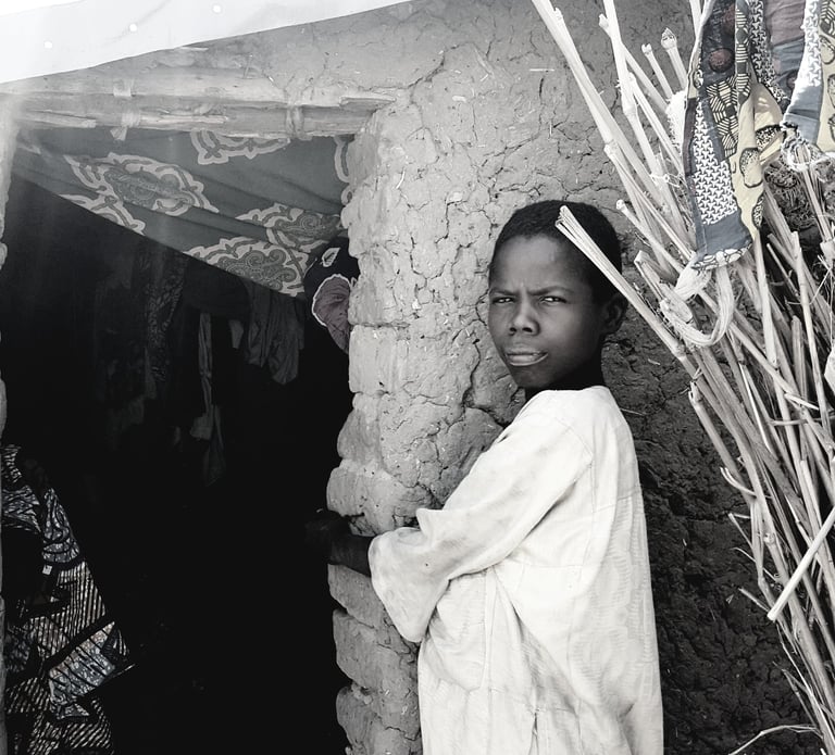 a boy in a white robe standing in front of a stone wall