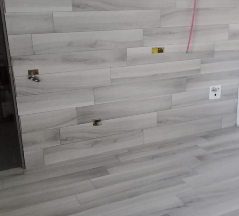 Modern light grey wood-look ceramic tile installation on a bathroom wall and floor during renovation.
