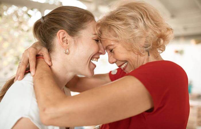 a woman in a red shirt is hugging her mother