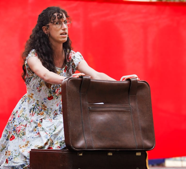 comédienne chanteuse sur scène équipée d'un micro serre tête, en train d'ouvrir une valise