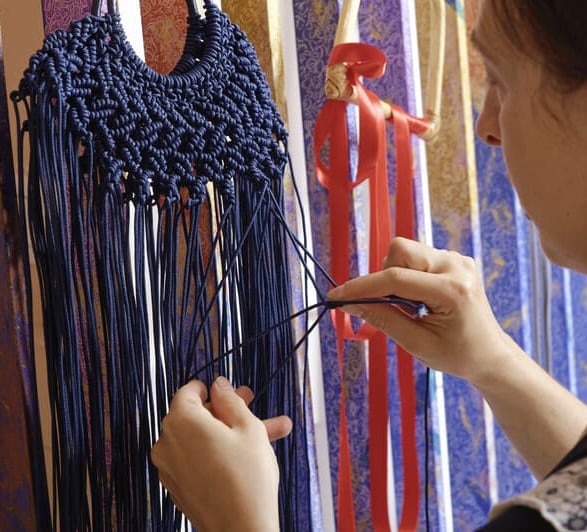 chica tejiendo un macrame de hilo azul