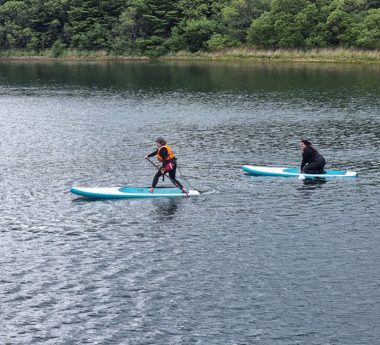 A stand up paddle board coach demonstrating to a student
