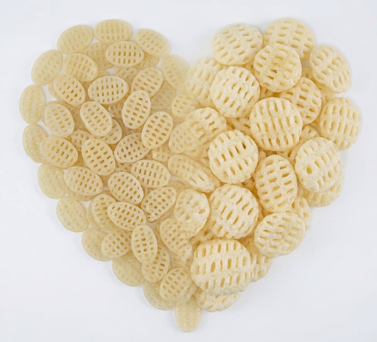 Heart-shaped pile of raw and fried potato lattice chips on a white background.