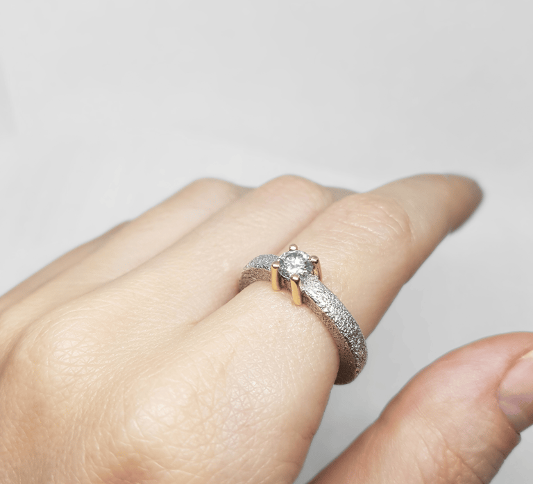 a person's hand holding a ring with a diamond