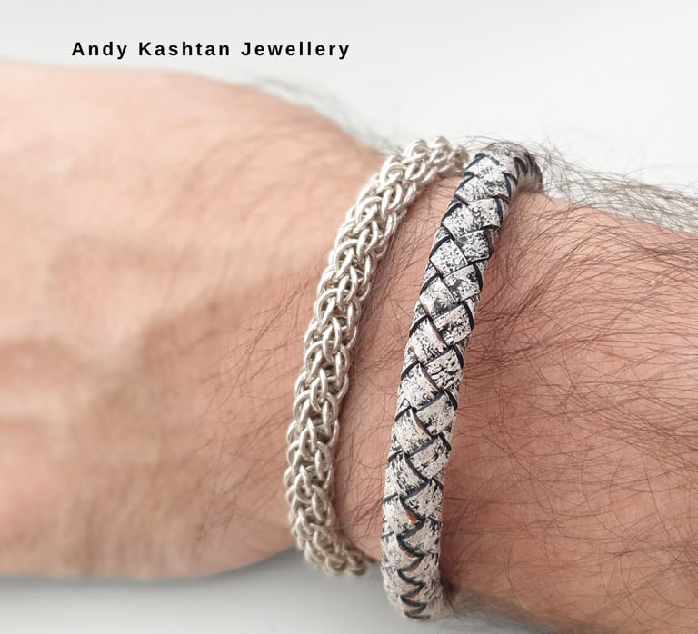 Handcrafted sterling silver chain and woven leather designer bracelets worn on a man's wrist.